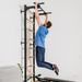 Man hanging from the steel pull-up bar on a black BenchK wall bar, demonstrating its stability and function.