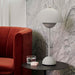 white &Tradition VP3 Flowerpot Table Lamp on side table beside red sofa.
