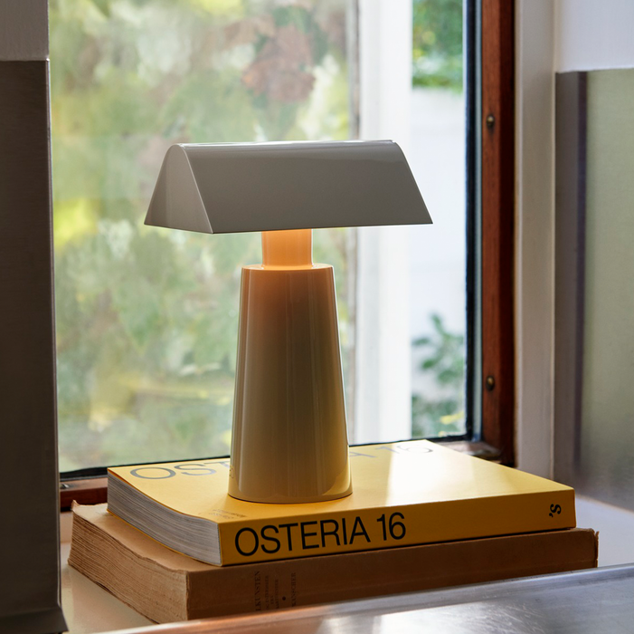 Silk Grey &Tradition MF1 Caret Portable Table Lamp on a Stack of Books by a Window