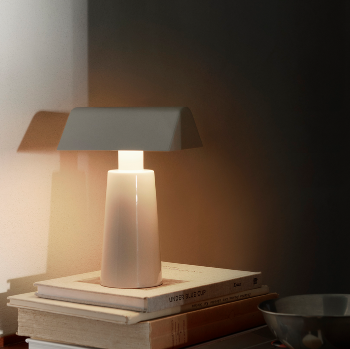 White &Tradition MF1 Caret Portable Table Lamp Illuminating Books in a Dark Setting